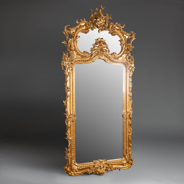 Exquisite Rococo-style giltwood mirror with  intricate carvings and an opulent  asymmetrical crest.