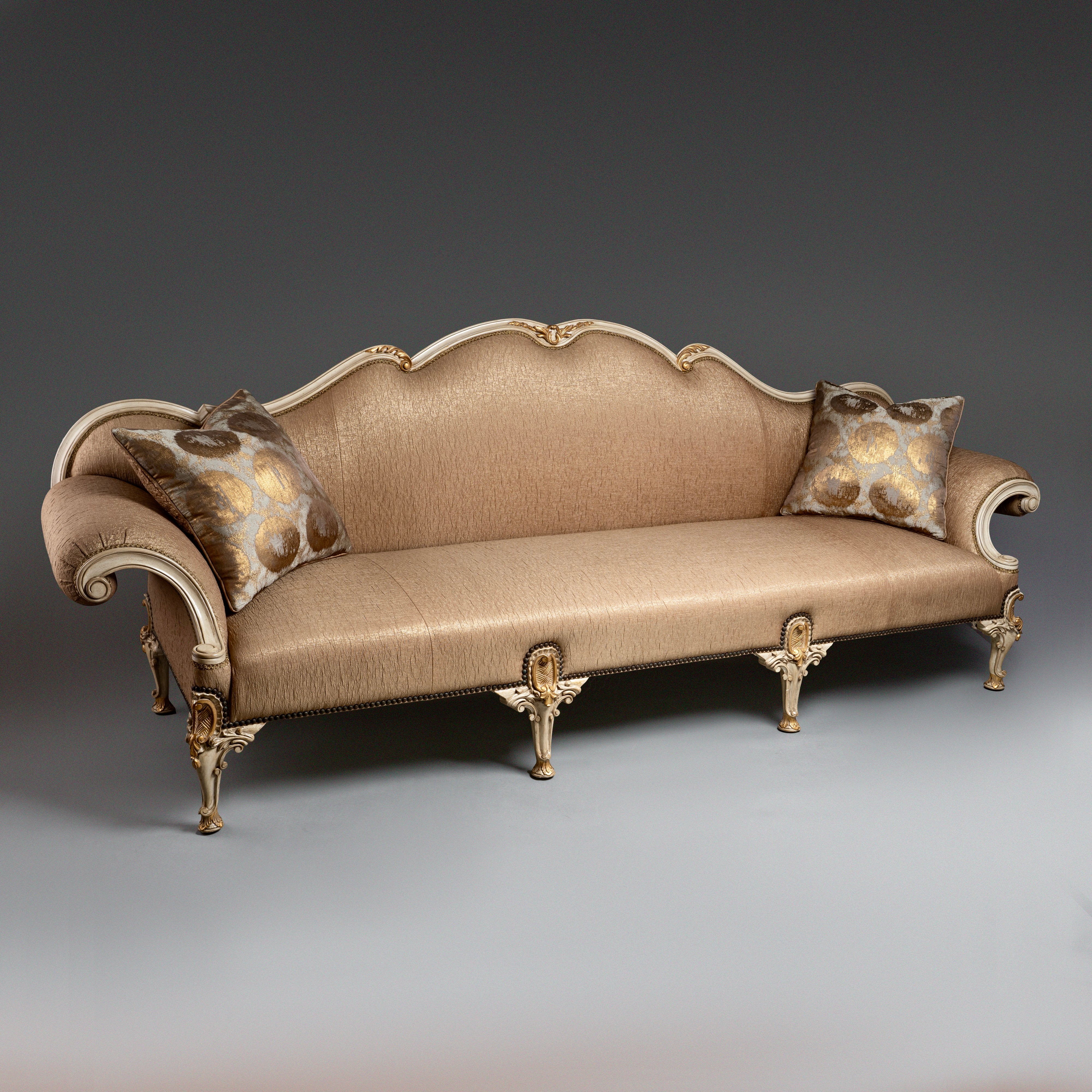 A regal Louis XV-style sofa with intricate  carvings and opulent upholstery.