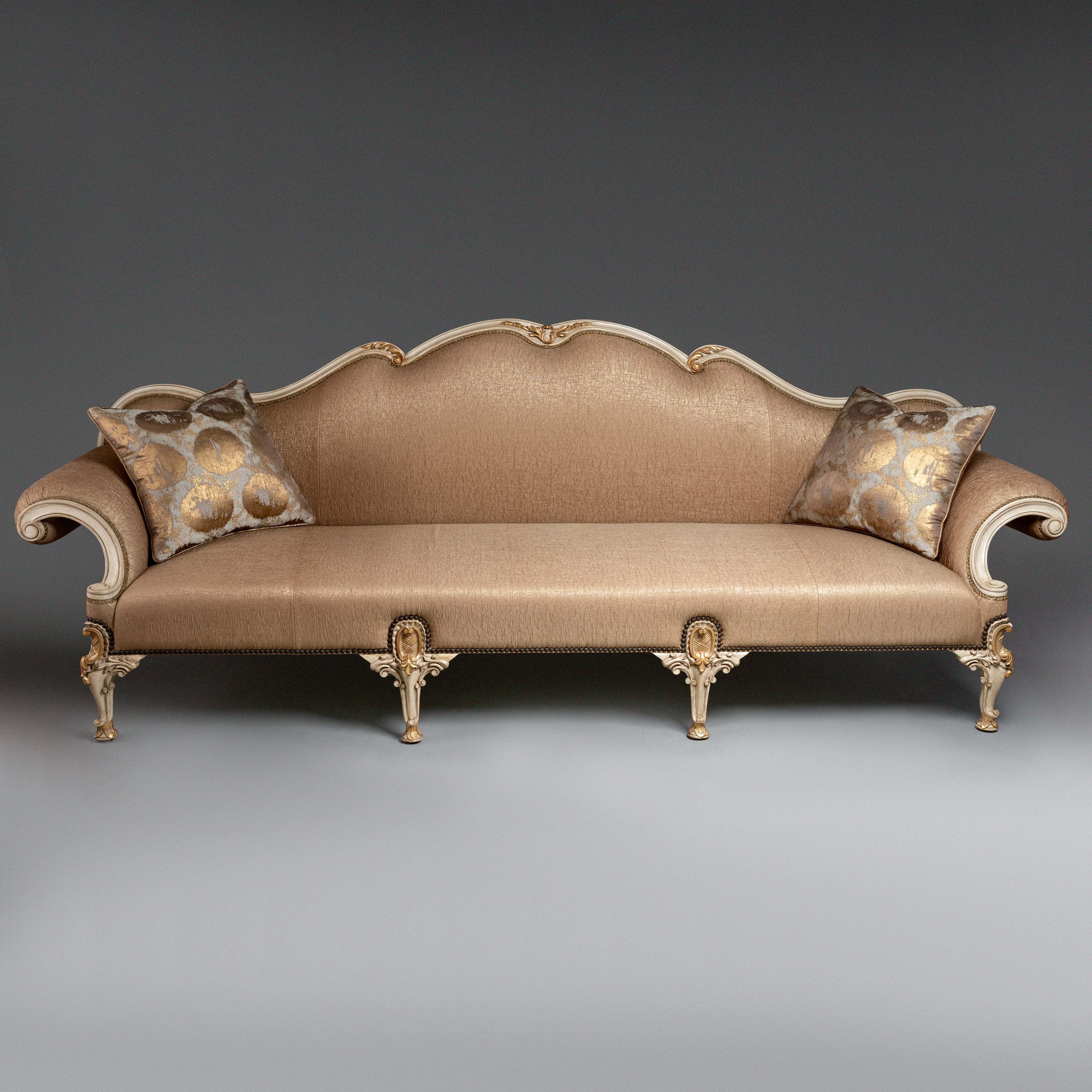 A regal Louis XV-style sofa with intricate  carvings and opulent upholstery.