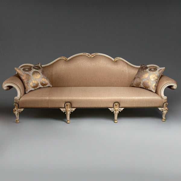A regal Louis XV-style sofa with intricate  carvings and opulent upholstery.