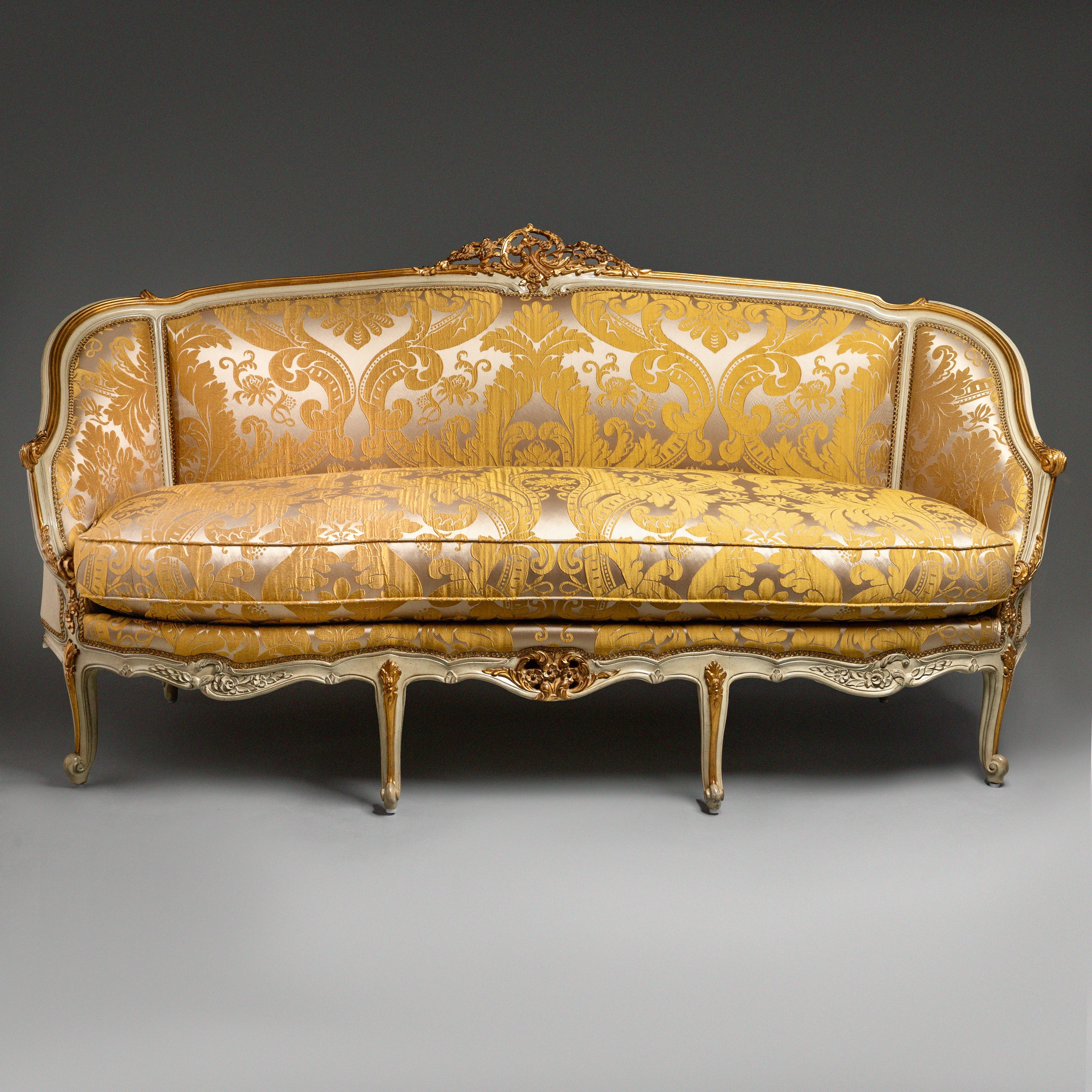 A luxurious Louis XV-style sofa with intricate  carvings and opulent gold damask  upholstery.