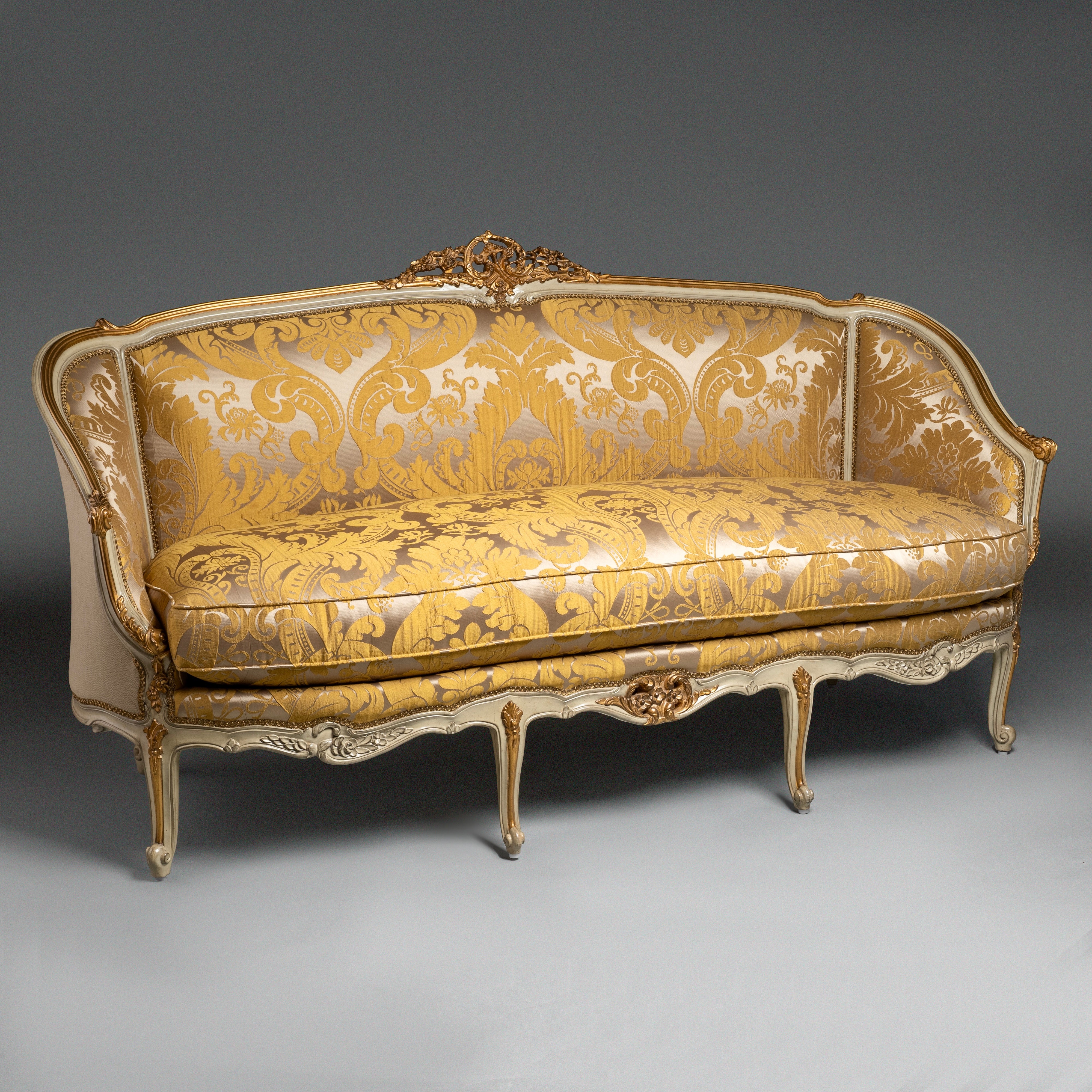 A luxurious Louis XV-style sofa with intricate  carvings and opulent gold damask  upholstery.